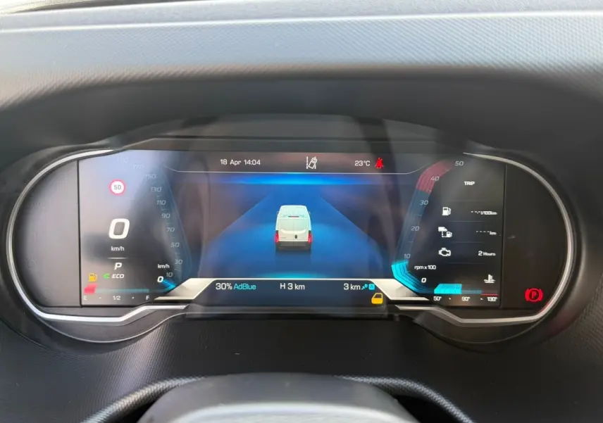 Vue rapprochée du tableau de bord numérique du Iveco Daily blanc, affichant la vitesse à 0 km/h et l'autonomie AdBlue.