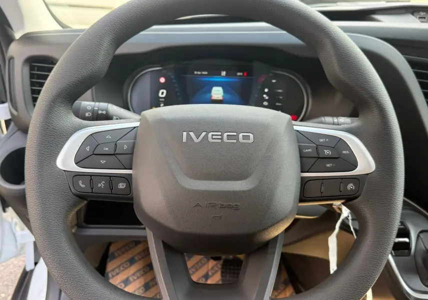 Vue rapprochée du volant noir de l’Iveco Daily 35S18 2026 avec commandes intégrées et tableau de bord numérique.