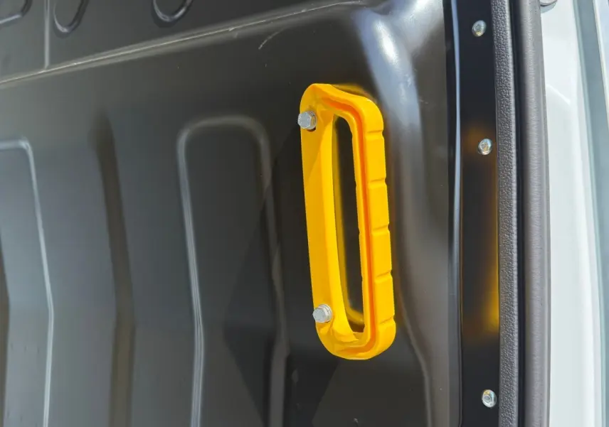 Poignée de maintien jaune fixée sur la paroi intérieure noire du véhicule utilitaire Iveco Daily blanc, vue en gros plan.