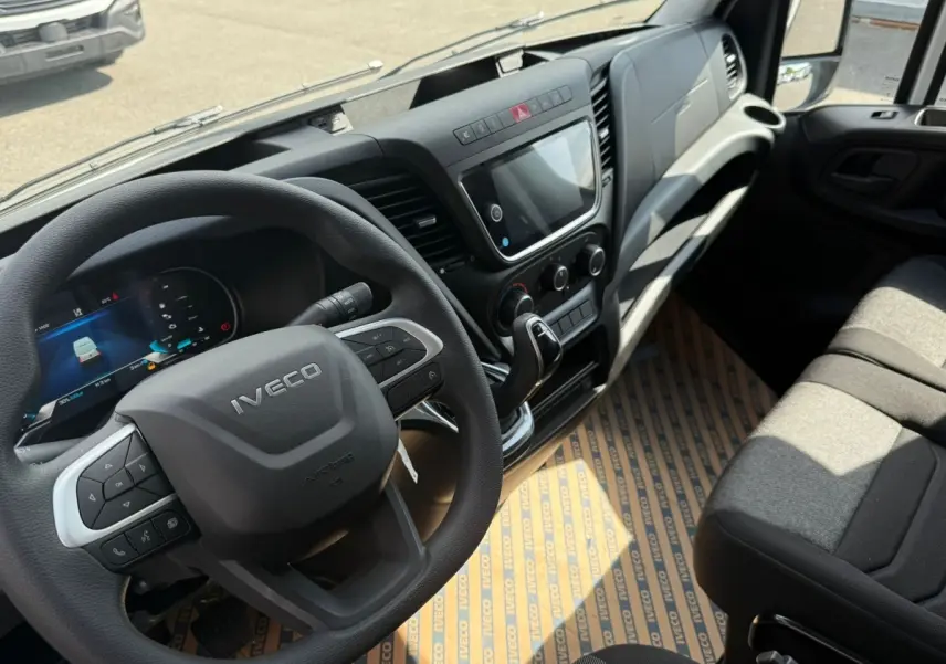 Vue intérieure côté conducteur de l'IVECO Daily blanc 2026, volant multifonction et tableau de bord moderne avec écran tactile.