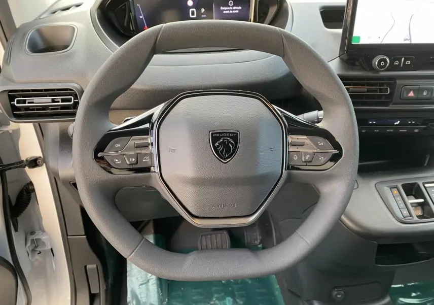 Vue intérieure centrée sur le volant Peugeot noir du Partner Fourgon blanc avec tableau de bord numérique et écran tactile.