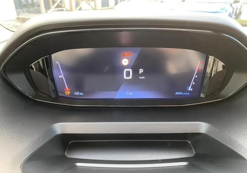Vue rapprochée du tableau de bord numérique du Peugeot Partner Fourgon blanc, affichant la vitesse à 0 km/h.