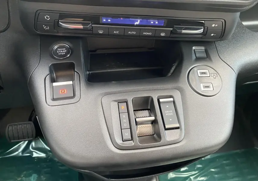 Vue rapprochée de la console centrale noire du Peugeot Partner Fourgon 2025 avec commandes de boîte et climatisation.