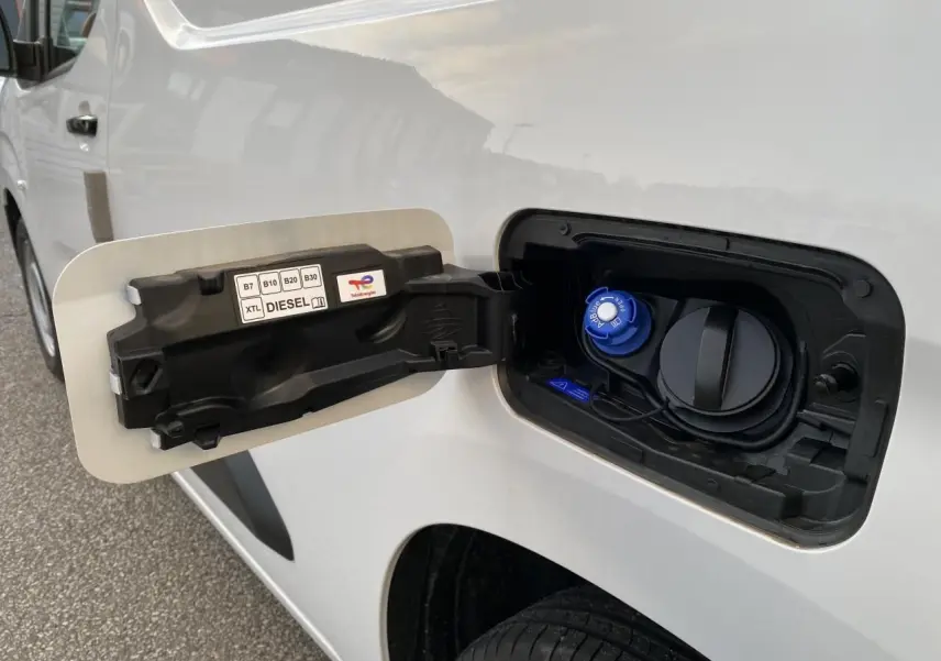 Vue rapprochée de la trappe à carburant côté gauche d'un Peugeot Partner Fourgon blanc avec bouchon diesel bleu.
