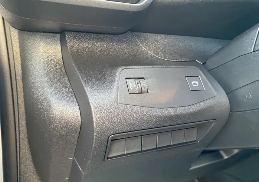 Détail du tableau de bord côté gauche du Peugeot Partner Fourgon blanc, avec commandes d'éclairage et boutons.