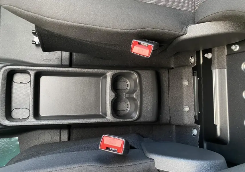 Vue plongeante sur la console centrale noire avec porte-gobelets et ceintures rouges du Peugeot Partner Fourgon blanc.