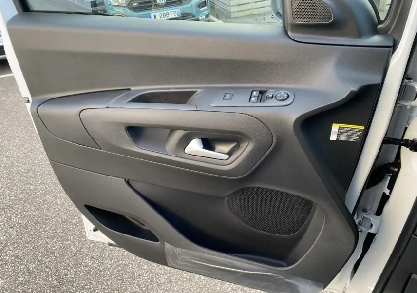 Vue rapprochée de la porte avant droite blanche du Peugeot Partner Fourgon avec commandes électriques et haut-parleur intégré.