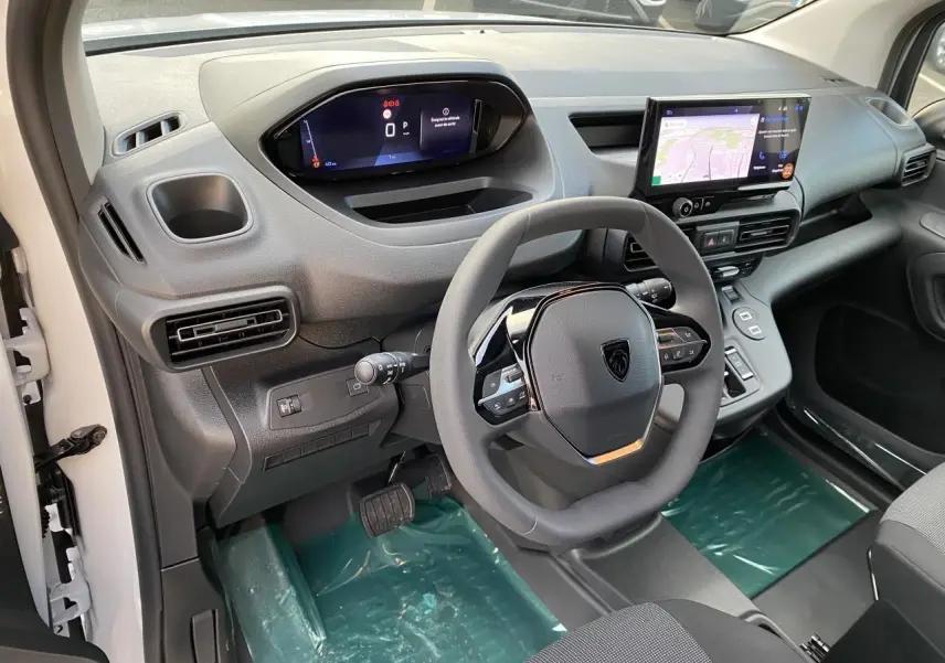 Vue intérieure côté conducteur du Peugeot Partner Fourgon blanc 2025, avec tableau de bord numérique et écran tactile central.
