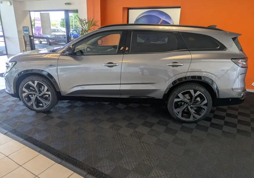 Profil côté gauche du Renault Espace VI E-Tech Full Hybrid 200 gris schiste avec jantes alliage 20 pouces Daytona et barres de toit noires.