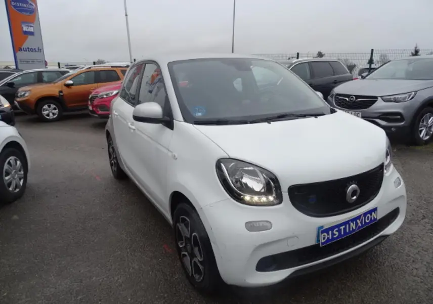 Vue 3/4 avant gauche d'une Smart Forfour électrique blanche avec calandre noire brillante et jantes alliage bicolores.