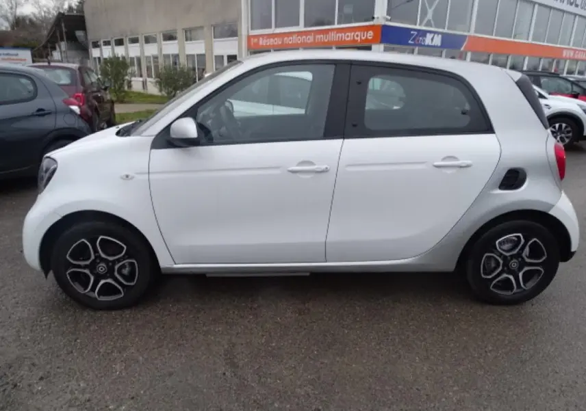 Vue latérale droite d'une Smart Forfour Electric Drive Prime blanche avec jantes alliage bicolores et calandre noir brillant.