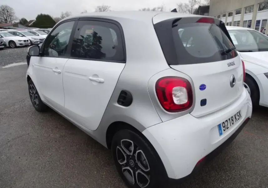 Vue 3/4 arrière droite d'une Smart Forfour Electric Drive blanche avec jantes alliage bicolores et logo EQ visible.