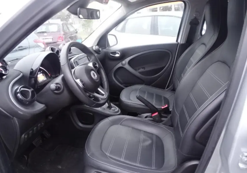Intérieur côté conducteur d'une Smart Forfour blanc, sièges cuir noir et volant multifonctions en vue rapprochée.