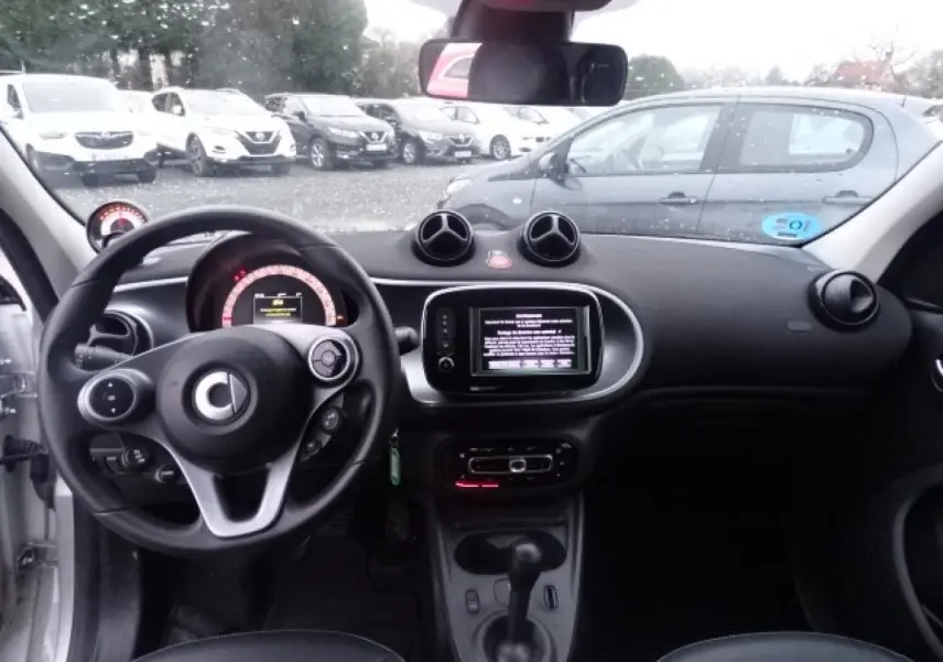 Vue intérieure avant du Smart Forfour Electric Drive Prime blanc, volant cuir multifonctions et écran tactile central visible.
