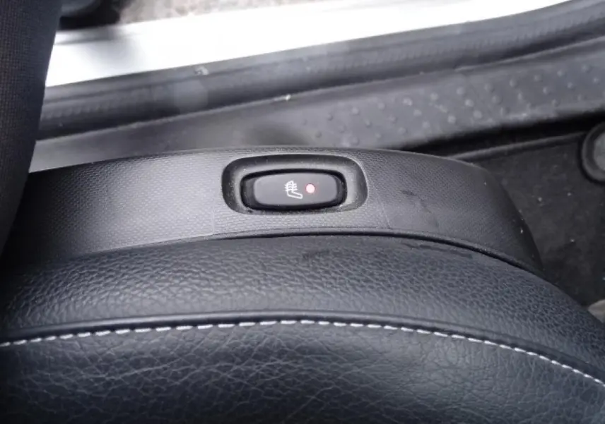 Gros plan sur le bouton de siège chauffant noir sur la sellerie cuir du Smart Forfour blanc électrique de 2018.