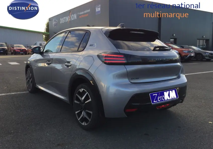 Peugeot 208 gris Artense métal vue 3/4 arrière droit, feux arrière LED et badge GT visibles sur parking.