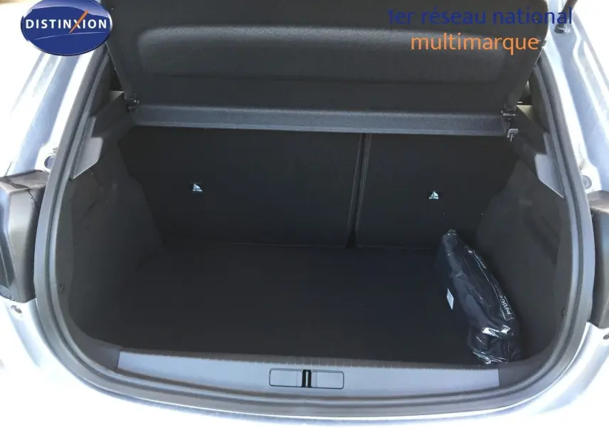 Coffre ouvert d'une Peugeot 208 gris Artense métal, montrant un espace de chargement vide avec une trousse noire sur le côté droit.