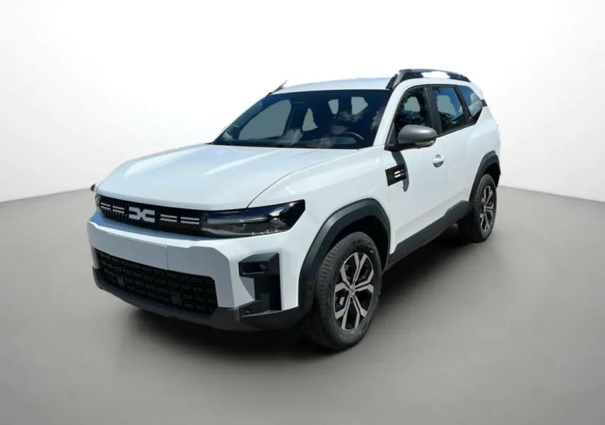Vue 3/4 avant d'un Dacia Bigster blanc glacier avec barres de toit et jantes alu 17 pouces sur fond neutre.