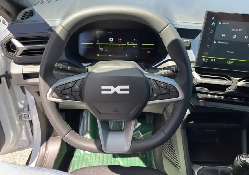 Vue rapprochée du volant cuir et du tableau de bord numérique du Dacia Bigster blanc glacier 2025, version mild hybrid.