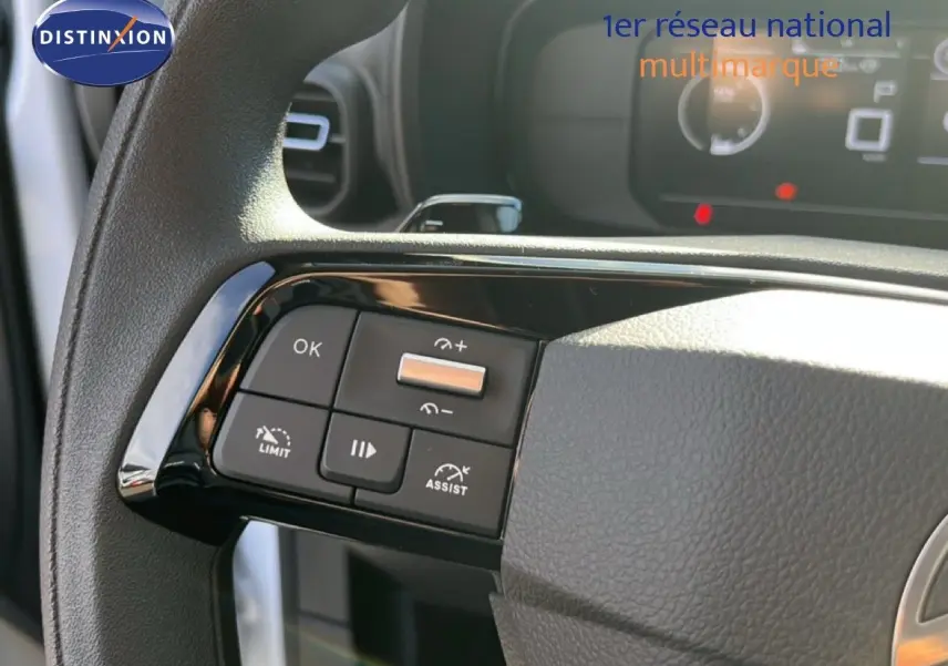 Gros plan sur les commandes au volant côté gauche du Citroën Berlingo blanc Icy, intérieur noir avec tableau de bord numérique.