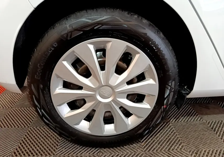 Gros plan sur la roue avant droite d'une Ford Fiesta blanche avec enjoliveur argenté et pneu EcoContact 6.