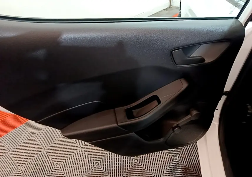 Vue intérieure de la porte avant droite noire d'une Ford Fiesta blanche 2022, avec poignée et commande manuelle de vitre.