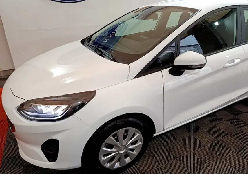 Vue 3/4 avant droit d'une Ford Fiesta blanche 2022 avec phares LED et rétroviseur blanc.