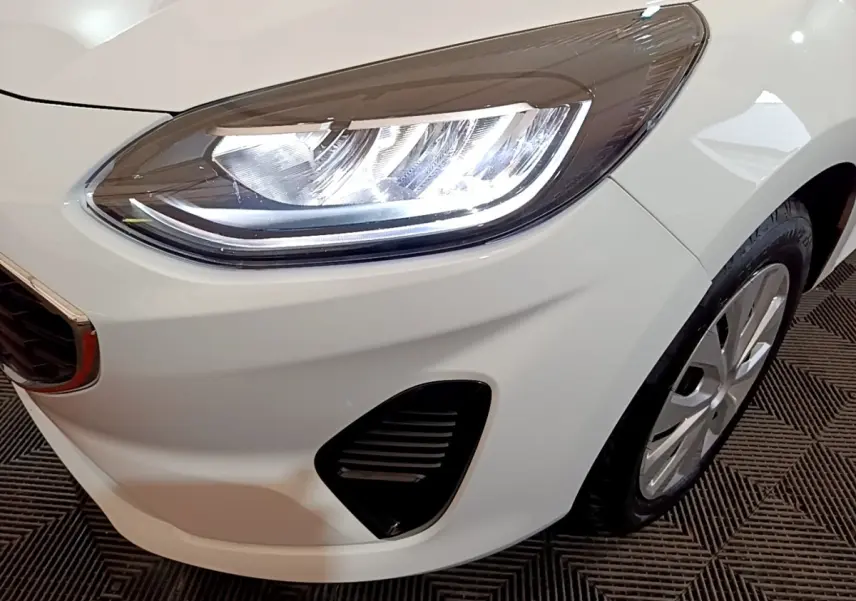 Gros plan sur le phare avant droit blanc d'une Ford Fiesta 2022 avec calandre et jante visibles.