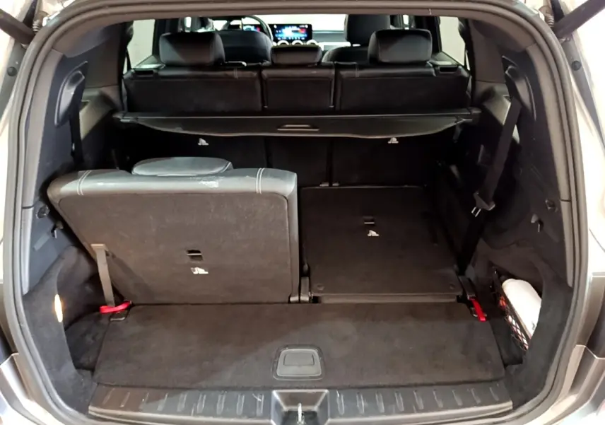 Coffre ouvert d’un Mercedes GLB 200 d gris foncé, montrant la 3ème rangée de sièges rabattable à distance, côté droit abaissé.