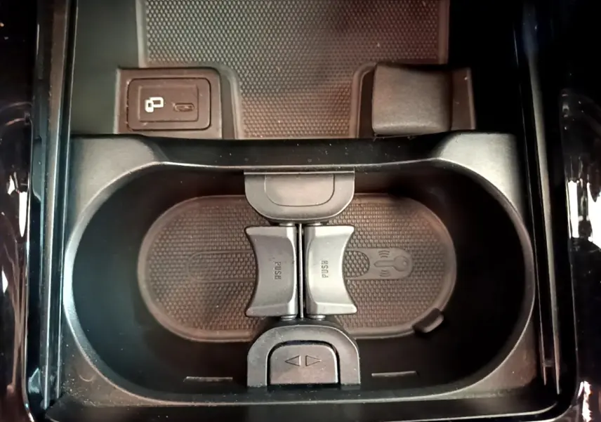 Gros plan sur le rangement central noir avec porte-gobelets et prise USB dans le Mercedes GLB 200 d gris foncé.