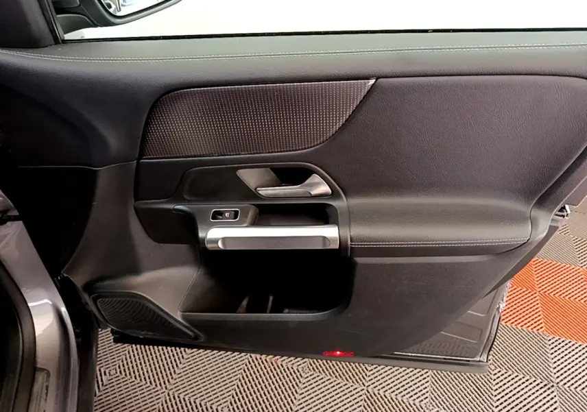 Vue intérieure côté gauche de la porte avant gris foncé du Mercedes GLB 200 d Business Line avec poignée argentée.