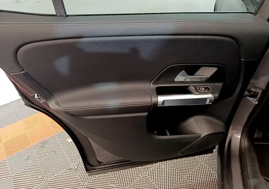 Vue intérieure de la porte arrière droite du Mercedes GLB 200 d Business Line gris foncé, avec poignée argentée et commandes électriques.