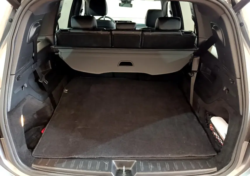 Coffre ouvert vu de l'arrière d'un Mercedes GLB 200 d Business Line gris foncé avec cache-bagages déployé.