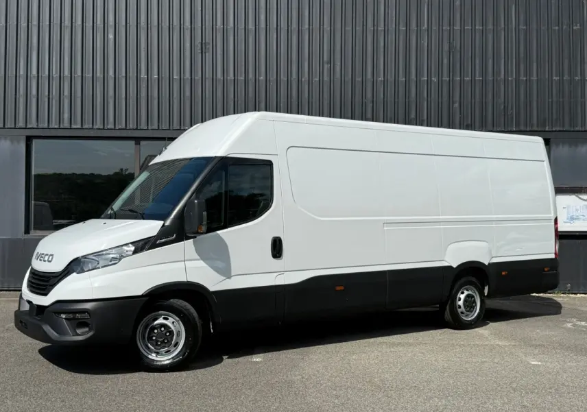 Fourgon Iveco Daily blanc vu de profil côté gauche, avec bas de caisse noir et porte latérale coulissante.