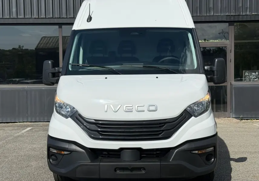 Vue frontale d’un utilitaire Iveco Daily blanc 2026 avec calandre noire et phares halogènes allumés.