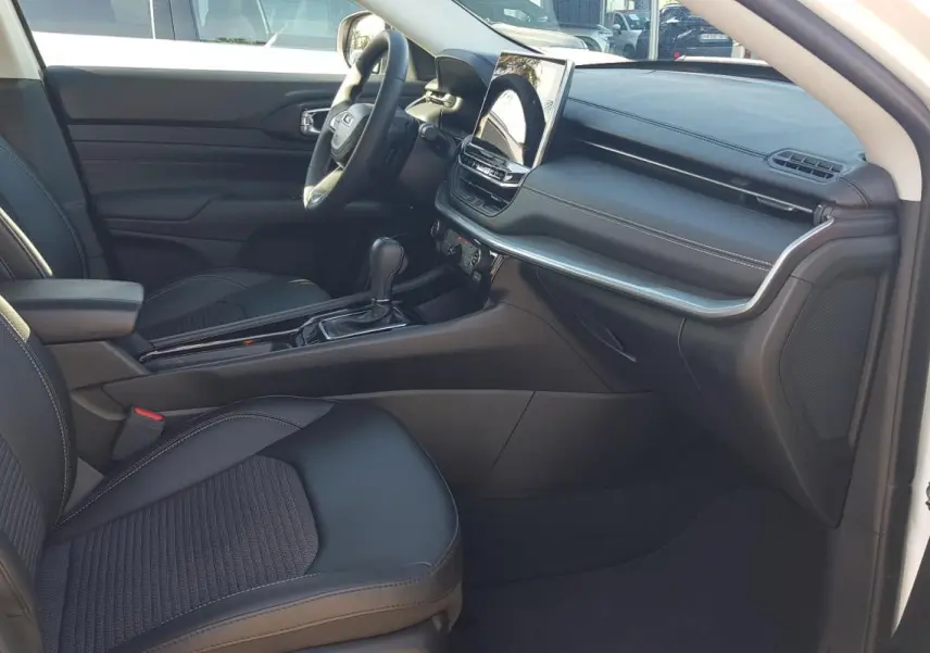 Vue intérieure côté passager du Jeep Compass blanc 2024, avec sièges noirs, accoudoir central et écran tactile.