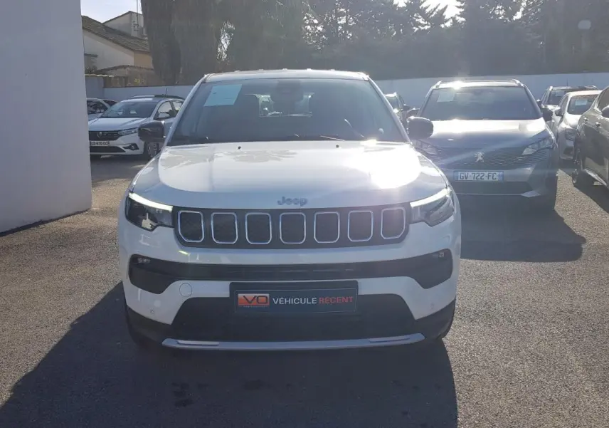 Vue avant d'un Jeep Compass blanc 2024 avec calandre à sept fentes et phares LED allumés.