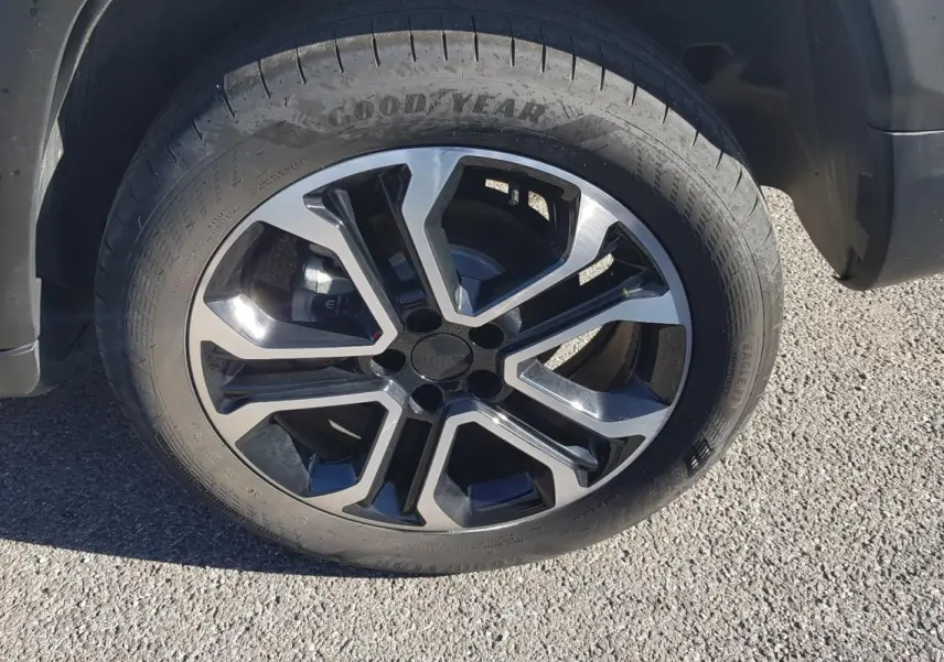 Gros plan sur la jante alliage 18 pouces noire et argent du Jeep Compass blanc, côté arrière droit.