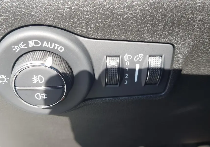 Gros plan sur la commande des phares et réglages d’éclairage du tableau de bord du Jeep Compass blanc 2024.