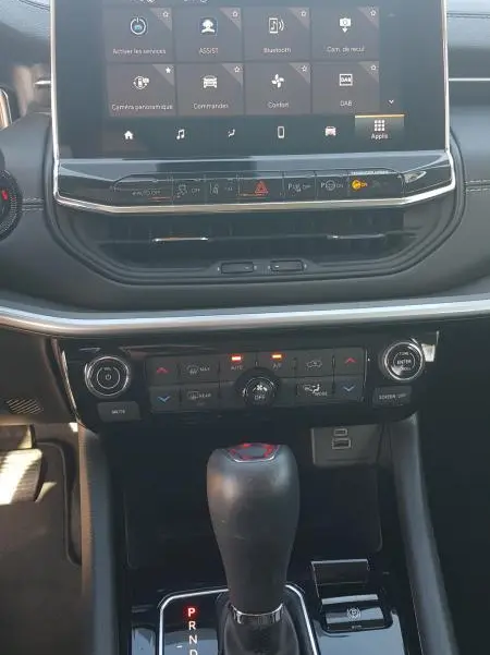 Vue rapprochée de la console centrale du Jeep Compass blanc 2024, avec écran tactile et levier de boîte auto.