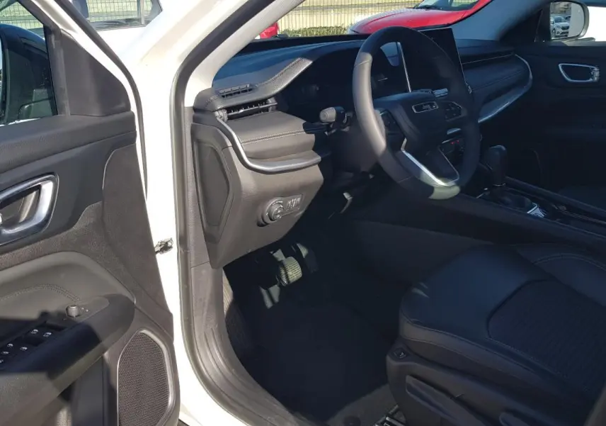 Intérieur du Jeep Compass blanc 2024 vu côté conducteur, avec tableau de bord et siège en cuir noir.