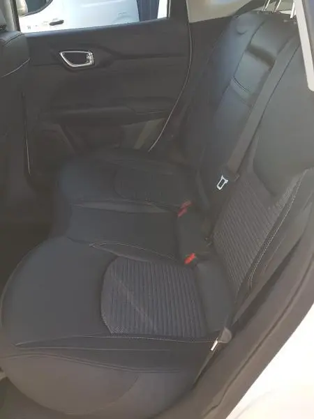 Vue intérieure côté arrière droit du Jeep Compass blanc 2024, montrant les sièges arrière noirs avec ceinture de sécurité.