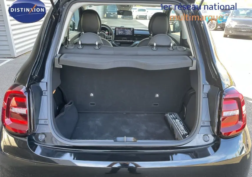 Vue arrière du coffre ouvert d'une Fiat 500 électrique noire Onyx 2023, avec intérieur et sièges visibles.