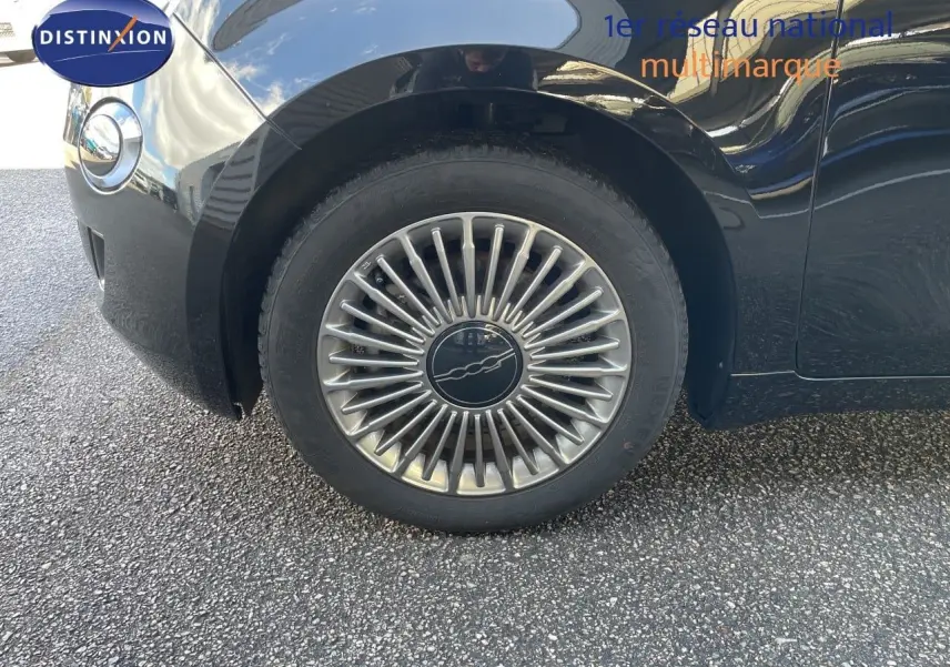 Gros plan sur la roue avant gauche d'une FIAT 500 électrique noir onyx, mettant en valeur la jante design étoilée.