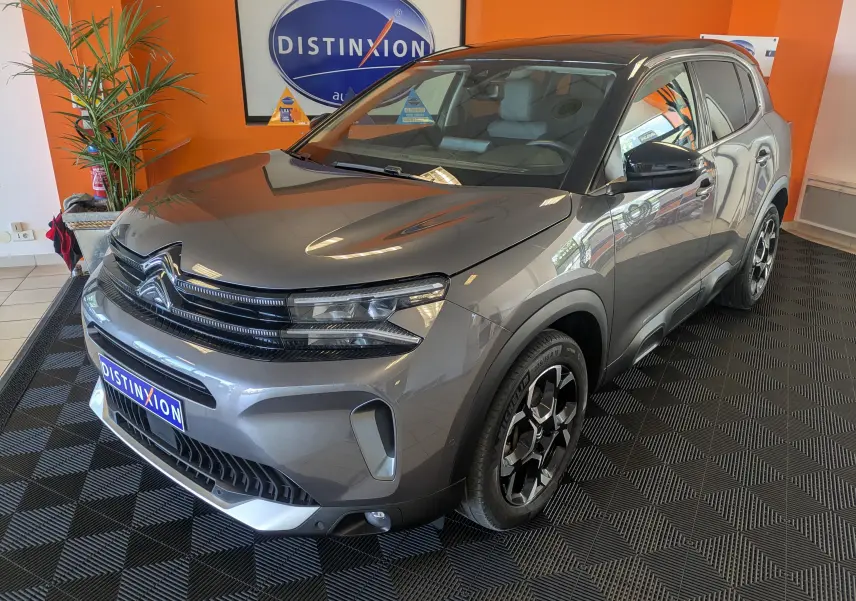 SUV Citroën C5 Aircross hybride gris platinium avec toit noir vu en 3/4 avant droit en intérieur showroom.