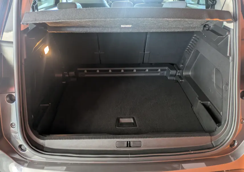 Coffre ouvert vu de l'arrière d'une Citroën C5 Aircross hybride gris platinium avec intérieur noir et cache-bagages.
