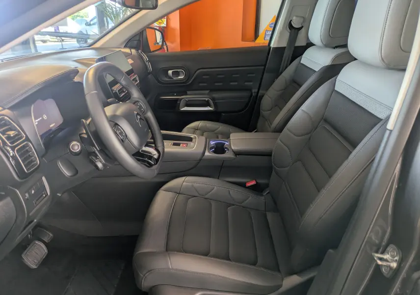 Vue intérieure côté conducteur du Citroën C5 Aircross hybride 2024, sièges en cuir gris et tableau de bord moderne.