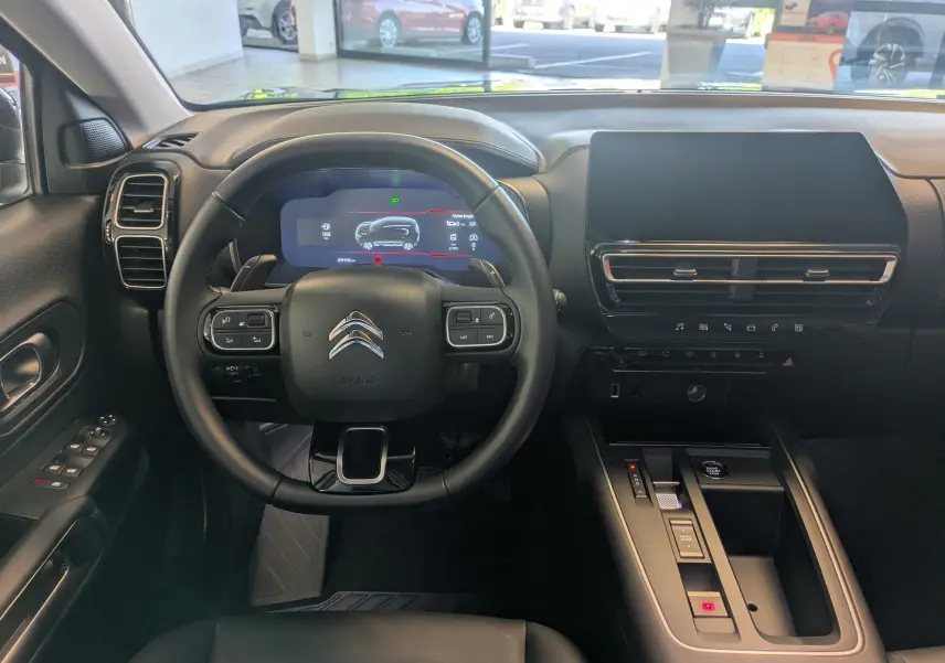 Vue intérieure centrée sur le volant cuir et tableau de bord numérique du Citroën C5 Aircross hybride 2024.