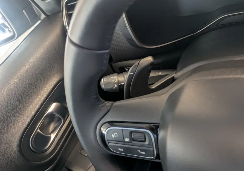 Gros plan sur le volant en cuir noir du Citroën C5 Aircross hybride, avec commandes intégrées côté gauche.