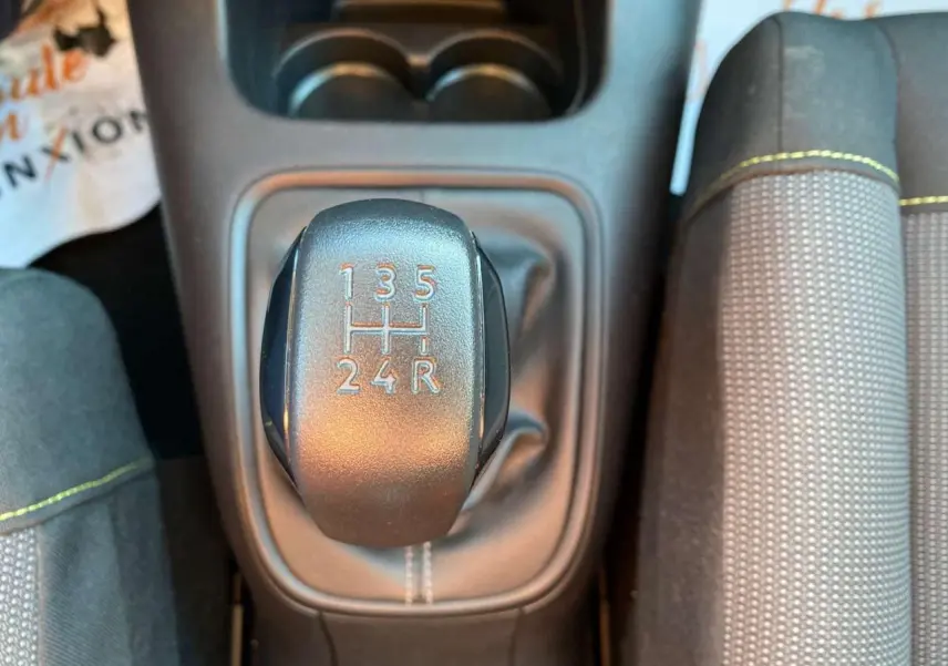 Le levier de vitesses manuel noir de la Citroën C3 2022, vue de dessus avec coutures blanches et siège gris à surpiqûres jaunes.